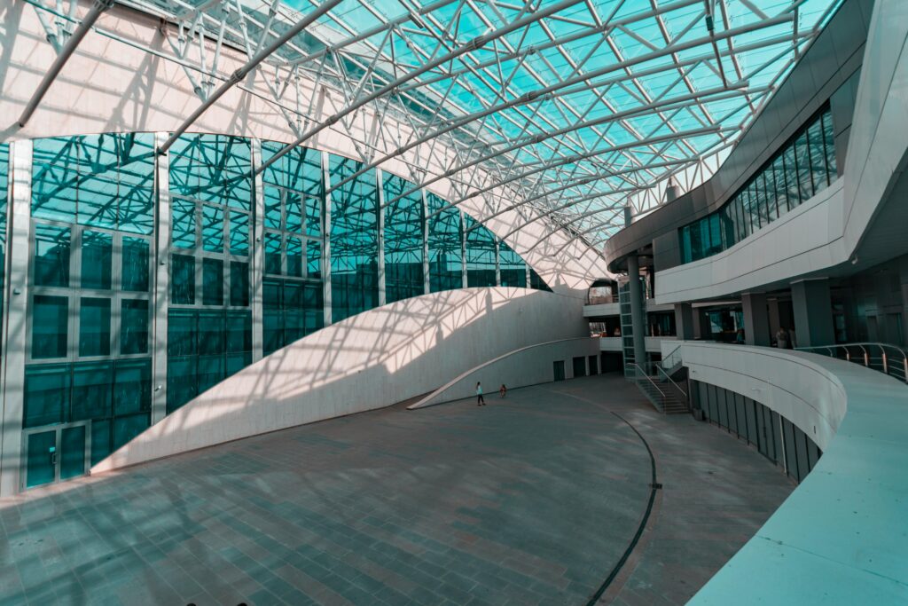 Spacious indoor atrium with modern glass and steel architecture, showcasing a futuristic design.